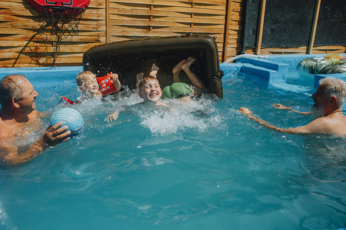 A family enjoying time together in a backyard swimming pool on a summer day.