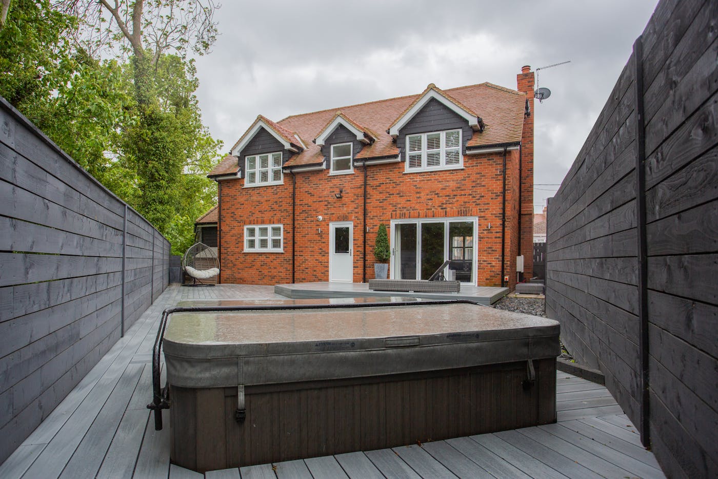 A spa installed on a brick-house backyard patio in a Midwestern neighborhood.